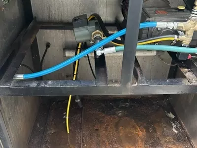 Internal view of a cold pressure washer cabinet showing contamination and moisture buildup caused by an unsealed plastic water tank. Constant condensation from hot water feed led to corrosion, dirt accumulation, and poor system hygiene.